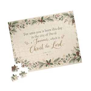 Puede incluir: Un rompecabezas rectangular con fondo color crema y un borde de ramas de pino verdes, bayas rojas y piñas. El texto dice: For unto you is born this day in the city of David a Saviour, which is Christ the Lord. Luke 2:11.