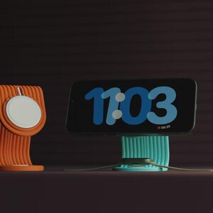 Può includere: Supporti di ricarica arancioni e turchese per telefono e smartwatch. Il telefono mostra l'ora 11:03 in blu. Il caricatore per smartwatch ha un pad di ricarica circolare bianco.