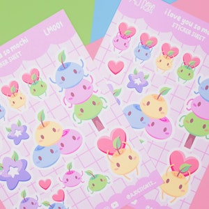 May include: Two sticker sheets with a pink background and a grid pattern. The sticker sheets feature a variety of cute cartoon mochi characters with different colors and expressions. The text "i love you so mochi sticker sheet" is printed on each sheet.