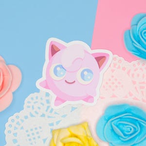 A kawaii vinyl sticker displayed on a pink and blue background.