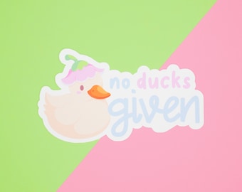 Puede incluir: Una pegatina blanca con un pato de dibujos animados que lleva una flor rosa en la cabeza. La pegatina dice "no ducks given" en texto azul y blanco.