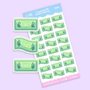 Puede incluir: Una hoja de pegatinas para planificador con billetes verdes en forma de dólar con diseños de corazón. Las pegatinas tienen el texto "It's pay day USD" y el nombre de la tienda. Sobre un fondo lila claro.