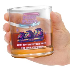 May include: A clear glass tumbler with a retro design. The glass features the text "Pork Plaza Mall" and a graphic of three futuristic tanks. The bottom of the glass reads "Where they slash their prices - and their customers!"