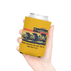 May include: Yellow can cooler with the text "SHOPPING MALL" and the phrase "WHERE SHOPPING CAN COST YOU AN ARM AND A LEG." Features a retro design of three tanks. The can cooler is held by a person.