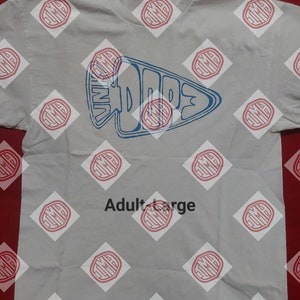 May include: A light gray t-shirt with a blue and white graphic that reads "Vintage Dope" in a stylized arrowhead shape. The shirt is labeled "Adult Large".