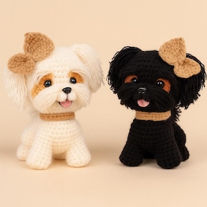 May include: Two crocheted dog figurines, one white and one black, each with a tan bow and collar. The white dog has tan accents around the eyes and ears. Both dogs have their tongues sticking out.