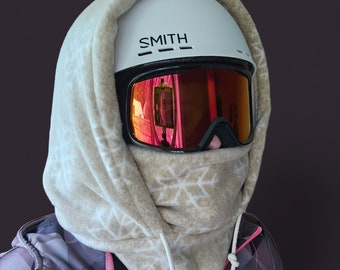 May include: A white ski helmet with a brown fleece neck gaiter. The helmet has a black visor with a red tinted lens and the word "SMITH" printed on the front.