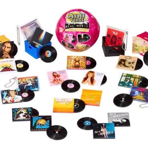 May include: A collection of miniature vinyl records and album covers featuring various artists, including a pink Mini Verse Real Music sphere, small plastic crates in yellow, blue, and black, and several individual record sleeves with colorful artwork.