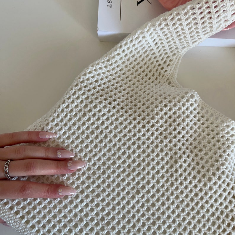 Puede incluir: Bolso tote de crochet blanco con un gran patr&oacute;n de malla. El bolso est&aacute; hecho de un material suave y ligero y tiene un interior espacioso.