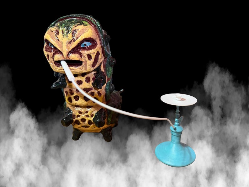 May include: A unique, hand-painted sculpture of a caterpillar-like creature with a hookah. The creature is yellow, brown, and green with blue eyes. The hookah is light blue with a white top and a white hose.