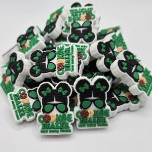 May include: A collection of white, black, and green shoe charms. The charms feature a cartoon character with sunglasses and a bow, with the text "COOKIE DEALER" and "how many boxes".