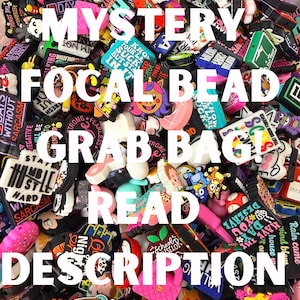 May include: A colorful assortment of focal beads, with various designs and text. The image features a "Mystery Focal Bead Grab Bag" with the text "Read Description". The beads are in various shapes and colors.