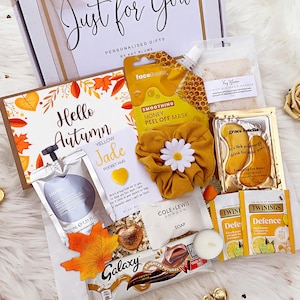 May include: A gift box set containing a honey peel-off mask, a yellow scrunchie with a daisy, gold eye masks, Twinings tea bags, a Galaxy chocolate bar, a soap bar, a lemon ginger bath salt packet, a yellow jade pocket hug, and a card.