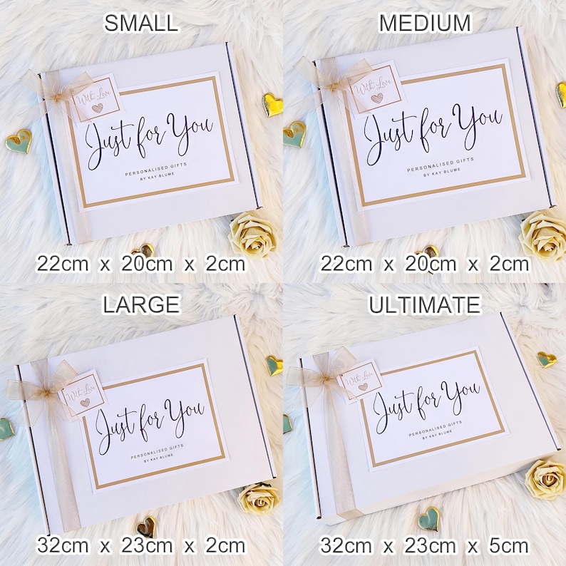 K&ouml;nnte beinhalten: Vier wei&szlig;e rechteckige Geschenkboxen mit der Beschriftung Small, Medium, Large und Ultimate. Jede Box hat ein gold umrandetes Etikett mit dem Text Just for You, Personalised Gifts by Kay Blume und einen kleinen Anh&auml;nger mit With Love.