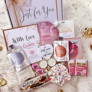 K&ouml;nnte beinhalten: Eine Geschenkbox mit der Aufschrift Just for You, die eine Face Facts rosa Tonmaske, einen Lanyah-Beutel, eine Rose Quartz Pocket Hug-Karte, ein herzf&ouml;rmiges Ornament mit der Aufschrift Self-care is self-love, zwei Teelichter, einen Galaxy-Riegel und Twinings-Tee enth&auml;lt.