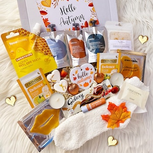 May include: A gift box containing a variety of items including a honey peel-off mask, three small pouches of hair care products, a lemon and ginger tea bag, bath salts, gold eye masks, a Galaxy chocolate bar, a lip balm, a soap bar, and candles.