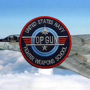 Op de afbeelding: Een ronde, blauwe, rode en witte geborduurde patch met de tekst "United States Navy Top Gun Fighter Weapons School".