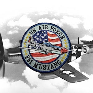 May include: A blue and white embroidered patch with the text "US Air Force P51 Mustang" and a red, white, and blue American flag with a silver P-51 Mustang airplane flying over it.