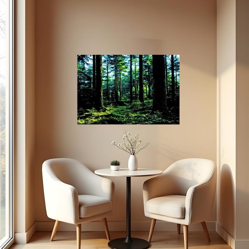 May include: A rectangular wall art print depicting a dense forest scene with tall dark tree trunks and vibrant green mossy ground. The artwork is displayed on a plain wall above a small round table with two cream-colored chairs and a white vase.