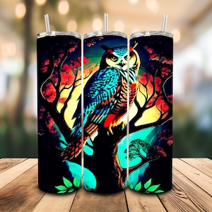 May include: Three stainless steel insulated tumblers with a vibrant owl design. The owl is perched on a tree branch, set against a backdrop of red, yellow, and black. Each tumbler has a clear straw.