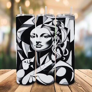Pode incluir: Três canecas de aço inoxidável com um design art déco em preto e branco com um retrato de mulher. Cada caneca tem uma palhinha prateada e um fundo geométrico em preto e branco. As canecas são cilíndricas e estão sobre uma superfície de madeira.
