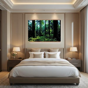 May include: A rectangular wall art print featuring a dense forest scene with tall dark tree trunks and vibrant green mossy ground, displayed above a beige upholstered bed frame with white bedding and two matching bedside lamps in a bedroom.