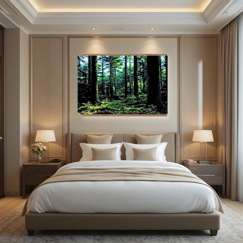 May include: A rectangular wall art print featuring a dense forest scene with tall dark tree trunks and vibrant green mossy ground, displayed above a beige upholstered bed frame with white bedding and two matching bedside lamps in a bedroom.