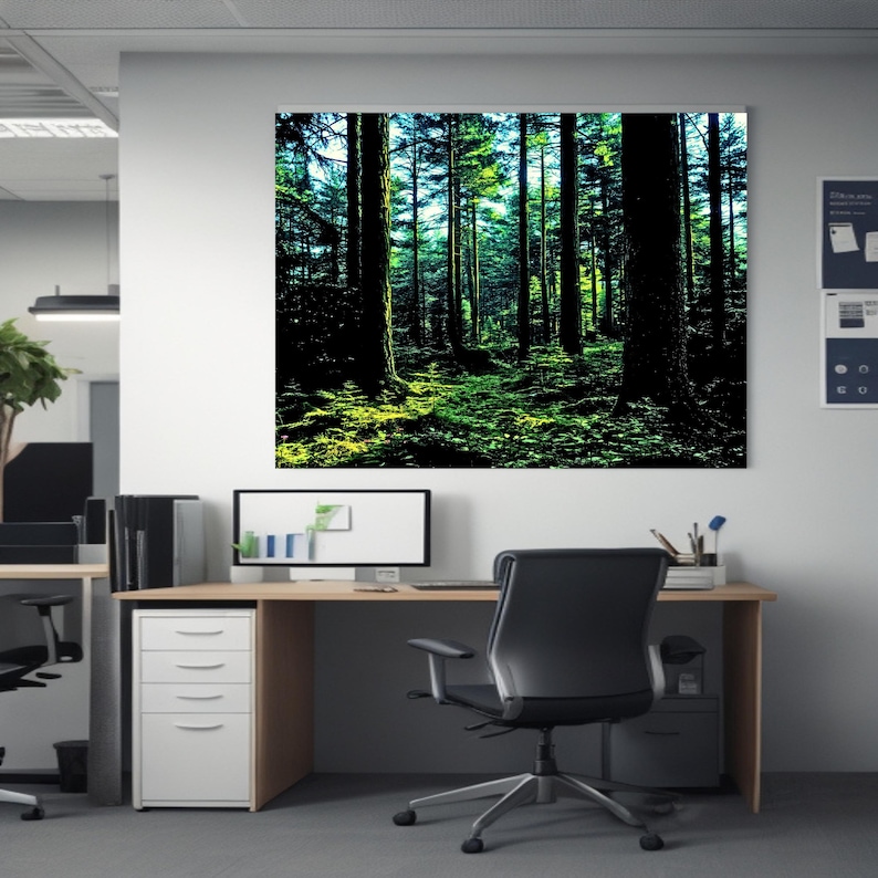 May include: A large rectangular wall art print featuring a dense forest scene with tall dark tree trunks and vibrant green foliage illuminated by sunlight, displayed on a white office wall above a wooden desk and a black office chair.