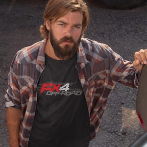 May include: A black t-shirt with a white graphic design that says "FX4 OFF-ROAD" in a stylised font. The graphic is in a red and white colour scheme.