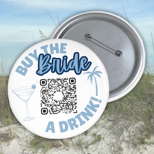 May include: White button with blue text that says "Buy the Bride a Drink!" with a blue palm tree and a martini glass. A QR code is in the center of the button.