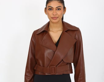May include: A brown faux leather jacket with a belted waist and long sleeves. The jacket has a  collared neckline and a  slightly cropped length.