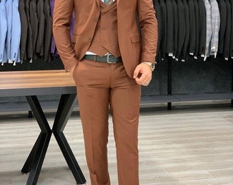 May include: A brown three-piece suit with a vest, a patterned tie, and a pocket square. The suit is worn by a person standing in a clothing store. The text "Weddingwearstore" is visible in the top right corner of the image.