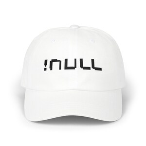 May include: A white baseball cap with a curved peak. The cap displays the word "!NULL" in a black, pixelated font across the front. The hat is made of a smooth material and has a button on top.