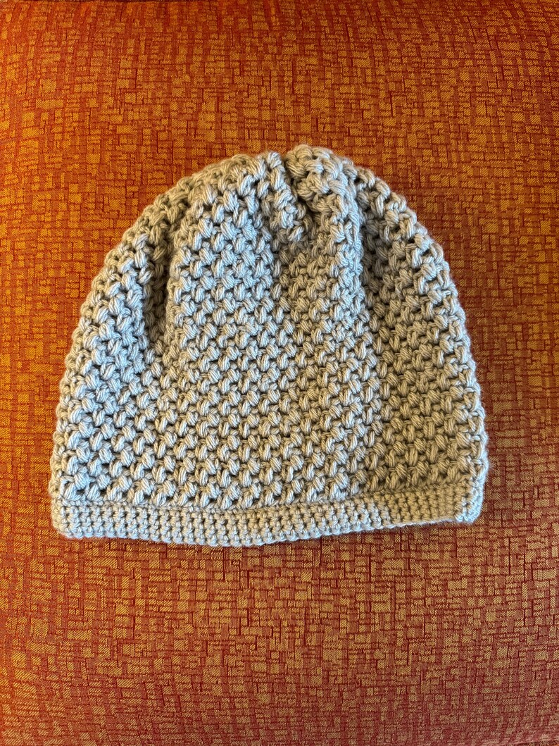 May include: A grey crocheted beanie hat with a textured stitch pattern.