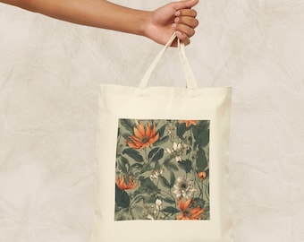 Op de afbeelding: Een beige canvas draagtas met een bloemenprint. De print toont oranje en witte bloemen met groene bladeren op een lichtgroene achtergrond.