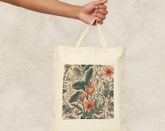 Op de afbeelding: Een witte canvas tote bag met een bloemenprint met oranje en groene bloemen. De tas heeft twee lange hengsels.
