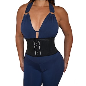 Peut inclure: Gaine de taille noire avec le mot "ICON" répété sur le devant. La gaine de taille est portée sur un haut bleu et un pantalon bleu.
