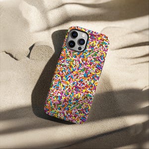 May include: A colourful phone case with a sprinkle pattern. The case is designed for an iPhone with a camera bump and a black border.