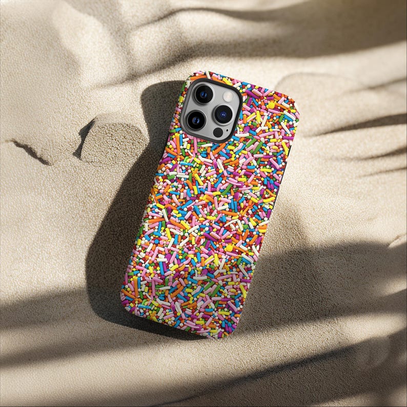 May include: A colourful phone case with a sprinkle pattern. The case is designed for an iPhone with a camera bump and a black border.
