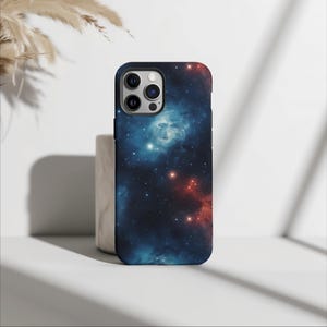 May include: A smartphone case displaying a colourful galaxy design. The case has a dark blue backdrop with red and blue nebulas and bright white stars. It has a black border and a camera cutout.