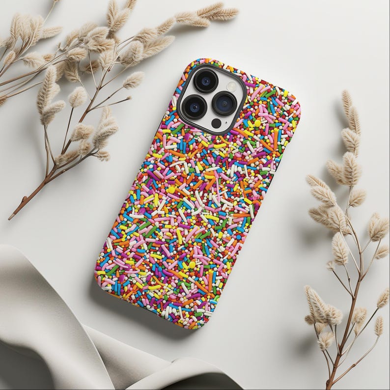 May include: A colourful phone case with a sprinkle pattern. The case is designed for an iPhone with a camera bump.