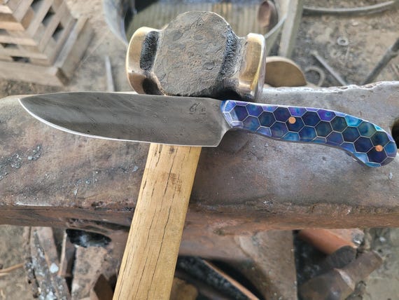 A hand-forged Damascus steel blade with flowing water-pattern steel and a leather sheath — the kind of knife a blacksmith spent days making by hand.