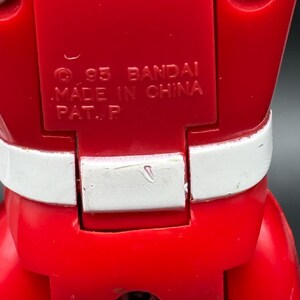 May include: A white ceramic mug with a black handle and the text "But First, Coffee" in a black, bold font. The mug is sitting on a wooden surface. The mug is approximately 4 inches tall.