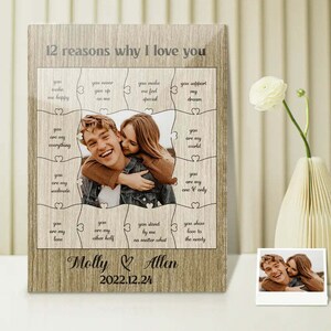 May include: A framed photo with a couple's picture in the center, surrounded by puzzle pieces with loving phrases. The text "12 reasons why I love you" is at the top, with the names "Molly & Allen" and the date "2022.12.24" at the bottom.