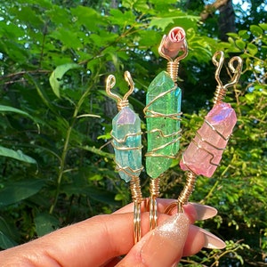 May include: Three gold-wrapped crystal hair clips. The crystals are iridescent and come in shades of pink, green, and blue. The clips are wrapped in gold wire and have a delicate, feminine design.