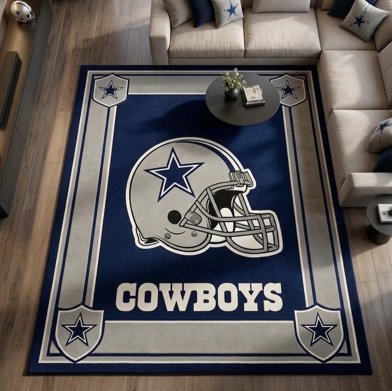 Puede incluir: Una alfombra rectangular con fondo azul oscuro y un gr&aacute;fico grande de un casco de f&uacute;tbol americano plateado en el centro. El casco muestra un logotipo de estrella azul. La palabra COWBOYS est&aacute; impresa en blanco debajo. Cuatro escudos con estrellas est&aacute;n en las esquinas.