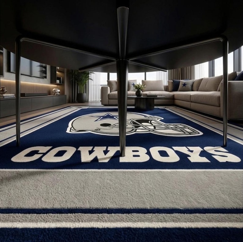 Puede incluir: Una alfombra rectangular con fondo azul profundo, un gr&aacute;fico grande de un casco de f&uacute;tbol americano plateado y un logotipo de estrella azul. La palabra COWBOYS est&aacute; impresa en letras may&uacute;sculas blancas grandes en el centro, con un borde blanco y plateado.