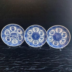 以下が含まれることがあります： 青と白の模様が施された3枚の丸い陶器製プレート。左のプレートには様々な瓶が描かれ、THE DECORATIVE JARN COLLECTIONという文字があります。右の2枚のプレートには様々な水差しが描かれ、THE DECORATIVE JUG COLLECTIONという文字があります。