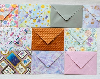 May include: Ten different patterned envelopes, each with a unique design. The envelopes are all closed and arranged in two rows of five. The envelopes are all different colors and patterns, including floral, geometric, and abstract designs.