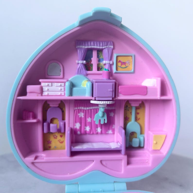 Pu&ograve; includere: Una casetta di giocattolo in plastica rosa e blu con un'apertura a forma di cuore. L'interno della casa &egrave; decorato con mobili e accessori, tra cui un letto, una cassettiera, una sedia e un comodino. La casa &egrave; progettata per essere un set di gioco per bambini.